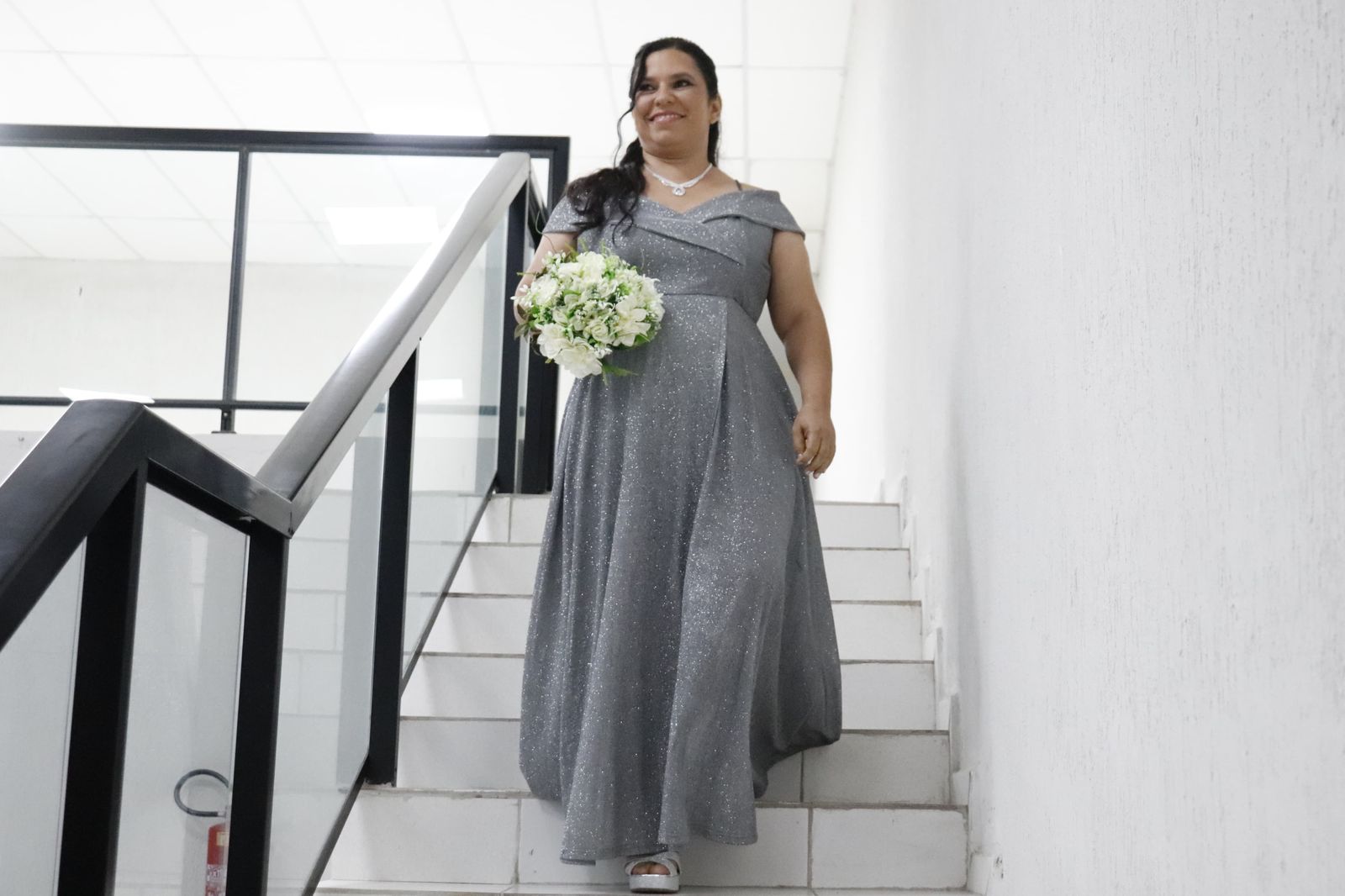 Noiva descendo a escada do mezanino com buquê