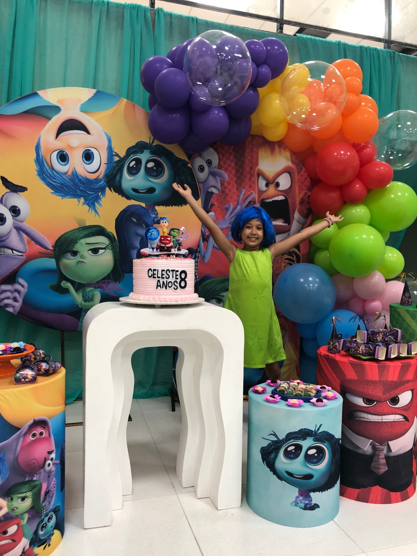 Aniversariante comemorando em frente ao painel temático com balões